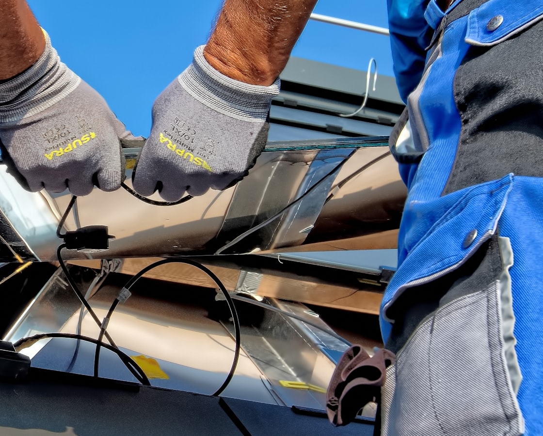 Row of solar panels newly installed on the roof of a modern suburban house in bright sunlight